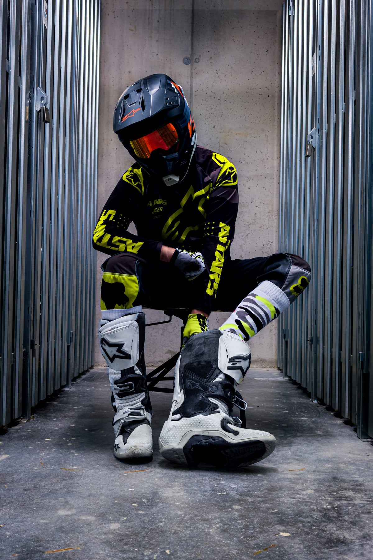 motard de motocross en tenue jaune néon avec bottes de cross et chaussettes MX jaune néon de sk8erboy, vu de face, assis dans les bottes