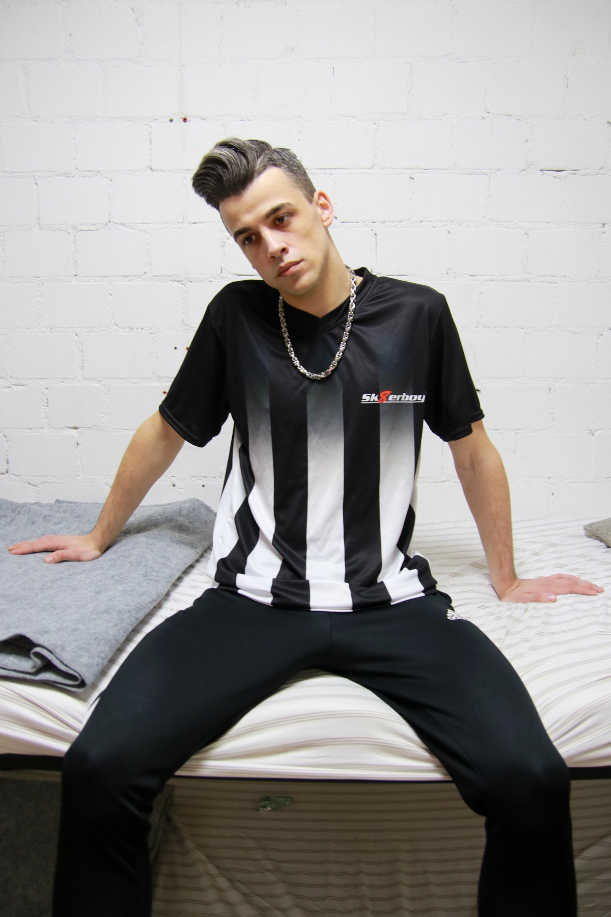 Urban look: Model sits in a bunk bed in a prison cell wearing the Sk8erboy® Tikot and shiny jogging pants