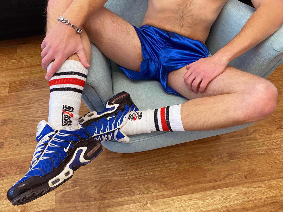 garçon allongé sur le canapé qui se tortille et frotte ses chaussettes de skateur malodorantes Sk8erboy contre son boxer bleu roi brillant, avec une large bande en satin