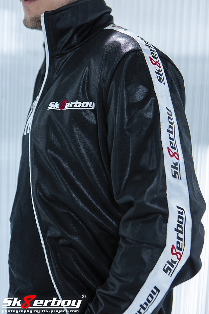 Garçon en gros plan avec survêtement Sk8erboy à veste brillante, de profil, avec grand bandeau sur le côté et logo sur la poitrine gauche