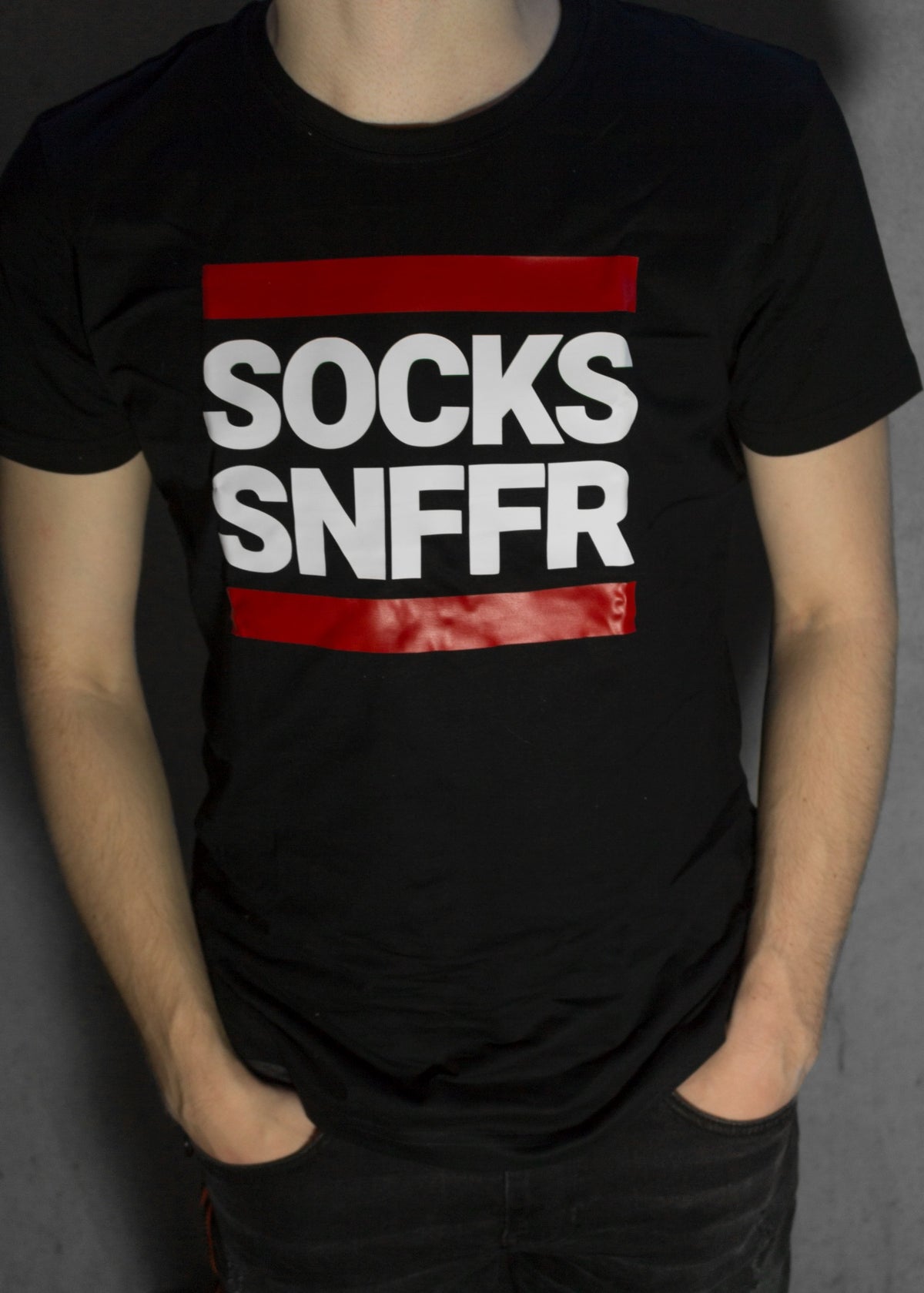 garçon portant un t-shirt noir avec l’inscription socks snffr en lettres blanches et des bandes rouges