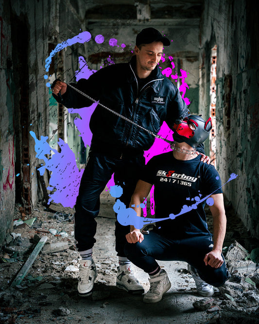 Zwei Juns in urbaner Lost-Place-Location mit Sk8erboy® Shirt und Fetish Gear, Sportswear und Hundemaske, inszeniert im Streetstyle-Fotoshooting mit Kette und urbanem Industrial-Look.