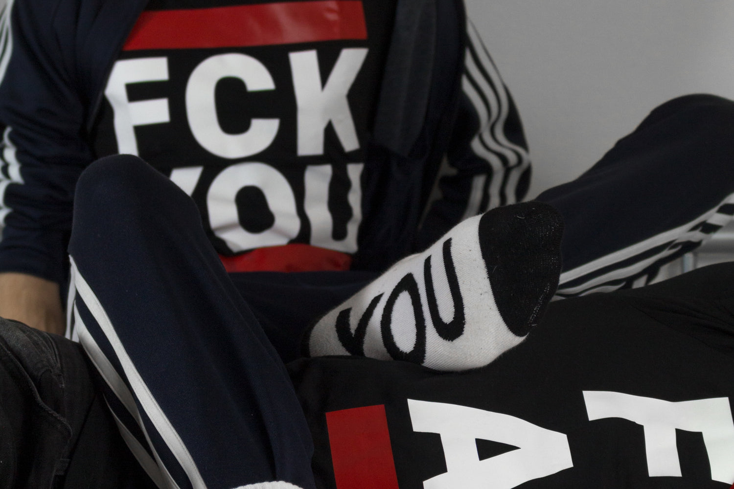 zwei gay jungs liegen im bett und tragen sk8erboy t-shirts mit der aufschrift fck you und fck abl mit socken von sk8erboy und adidas trainingsanzug