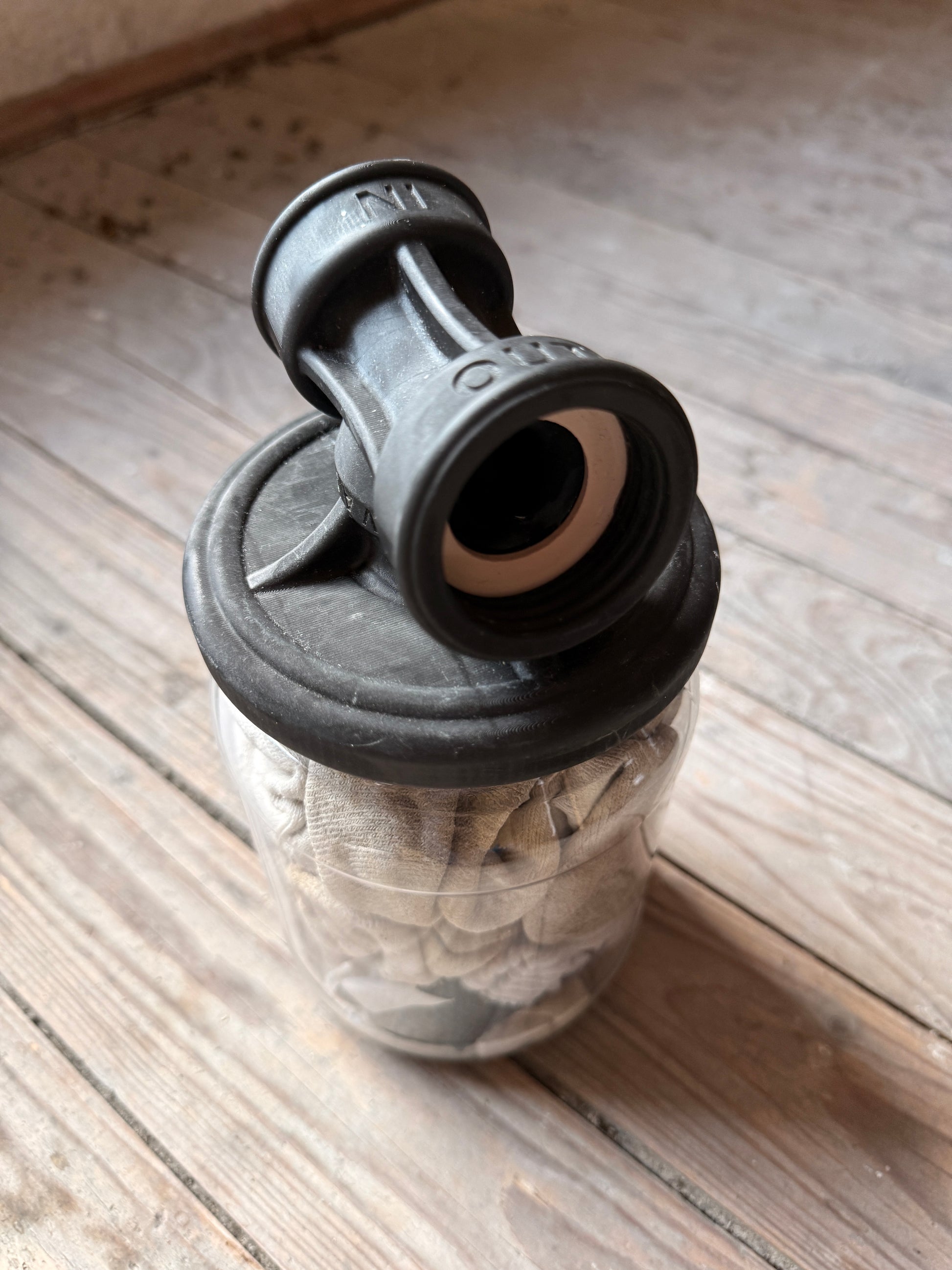 Nahaufnahme eines Sk8erboy Vast Sniffer Glases mit Sockenfüllung und schwarzem Aufsatzdeckel auf dem Holzboden.