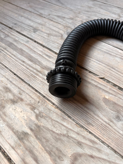 Detailaufnahme des schwarzen Vast Sniffer Schlauchs mit Schraubanschlüssen auf dem Holzboden.