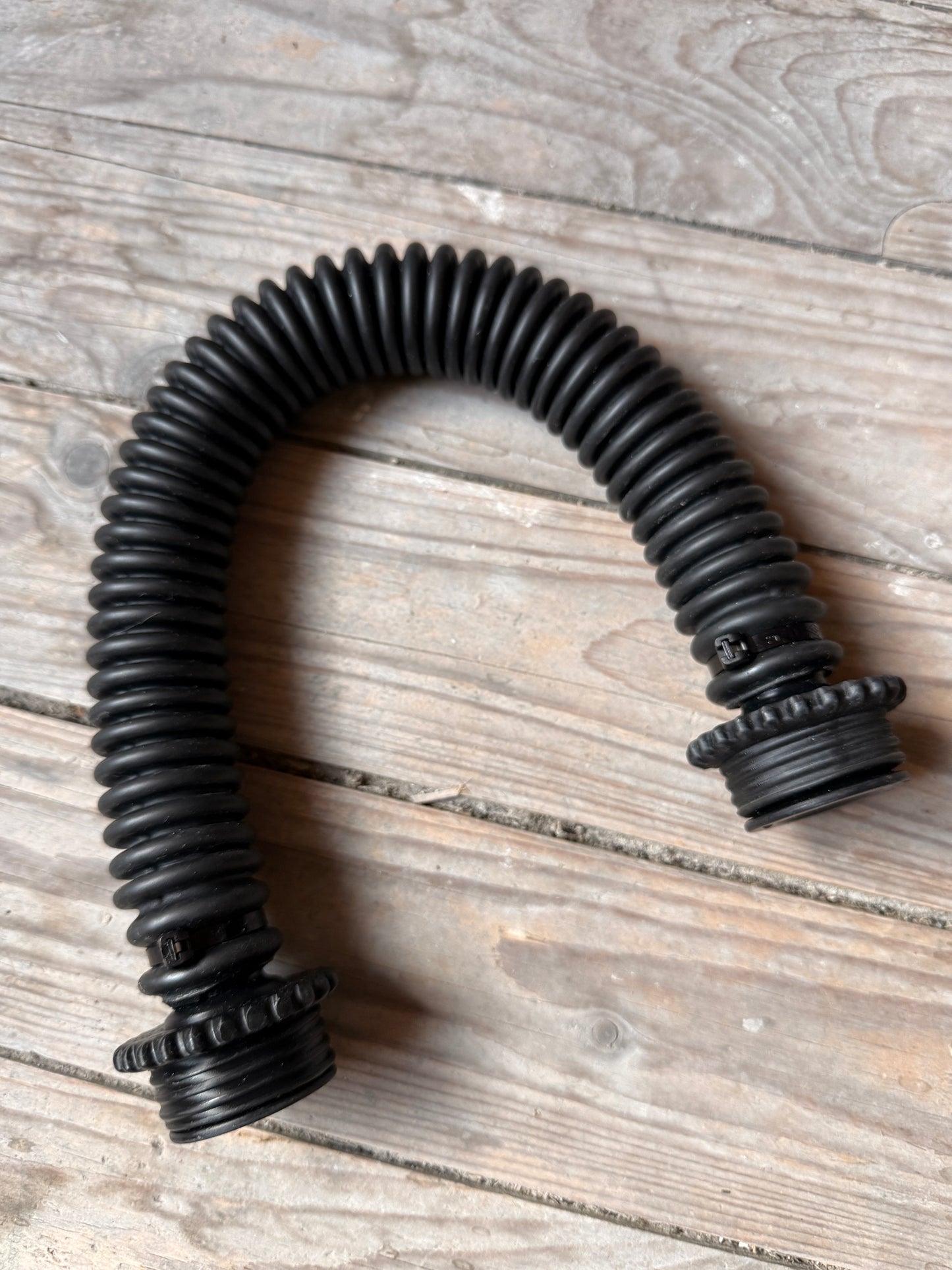 Komplette Ansicht des schwarzen Vast Sniffer Schlauchs in U-Form auf Holz.